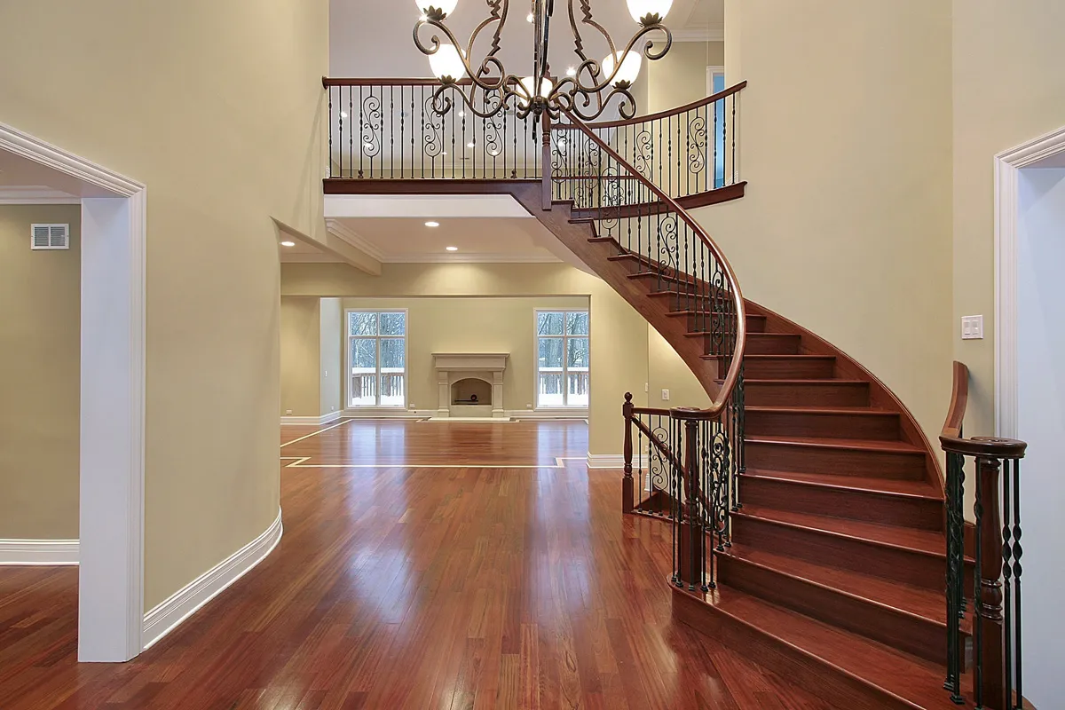 Curved staircase with a wood handrail and a balcony over a two-story foyer